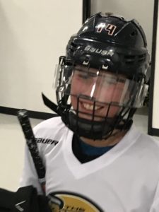 A teenaged player wearing a black hockey helmet